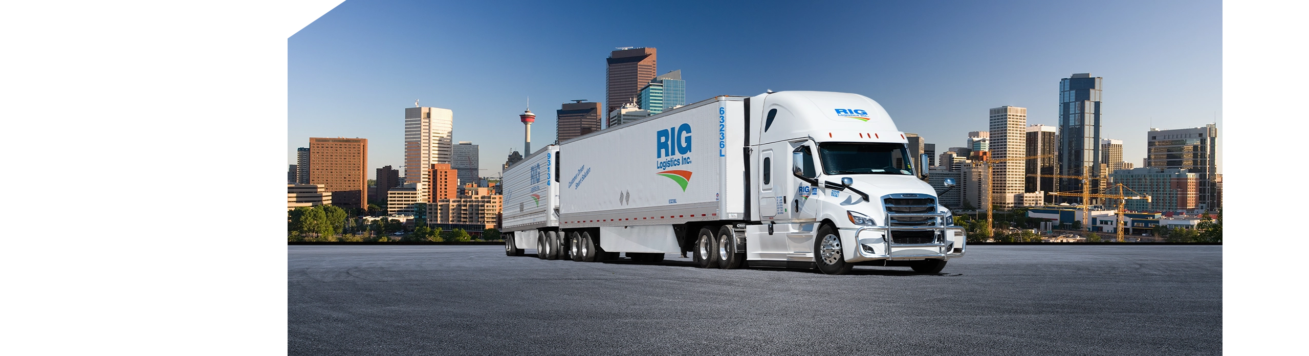 RIG Logistics long combination vehicle (LCV) driving in front of Calgary, Alberta cityscape